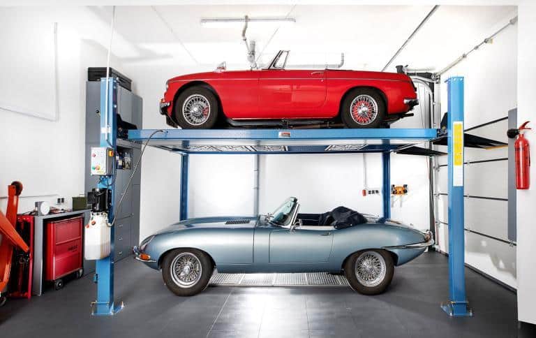 Roter und silbergrauer Oldtimer auf einem Parklift in einer BRAUN Keller Tiefgarage